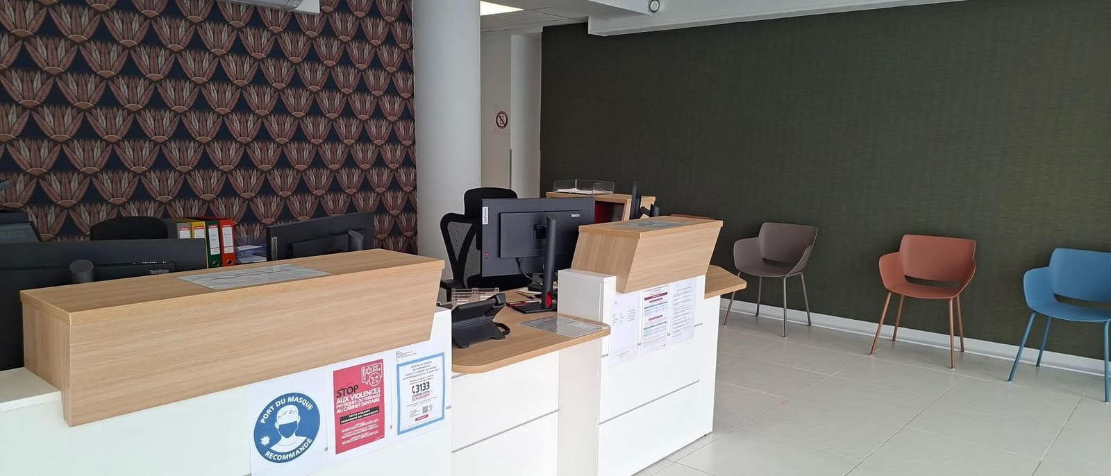 L'accueil du centre : comptoir en bois clair et espace d'attente avec des fauteuils gris, terracotta et bleu